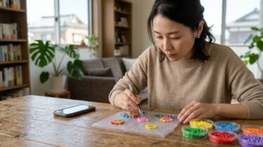 テーブルでカラフルなアイロンビーズを並べる大人の手元